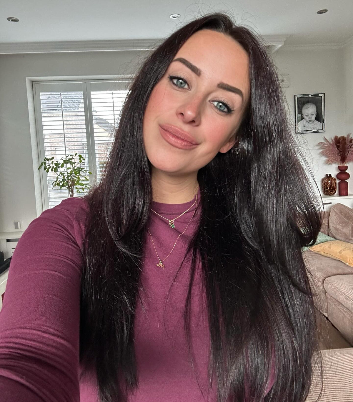 Portret van een glimlachende vrouw met lang donker haar in een paarse top.